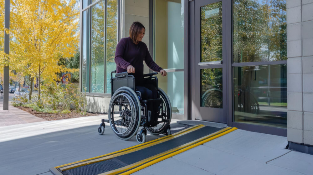 Mulher cadeirante na entrada de um prédio, próxima da porta