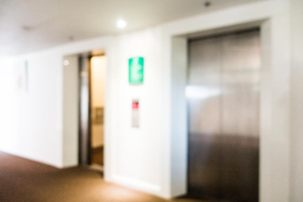 A imagem mostra dois elevadores em um corredor